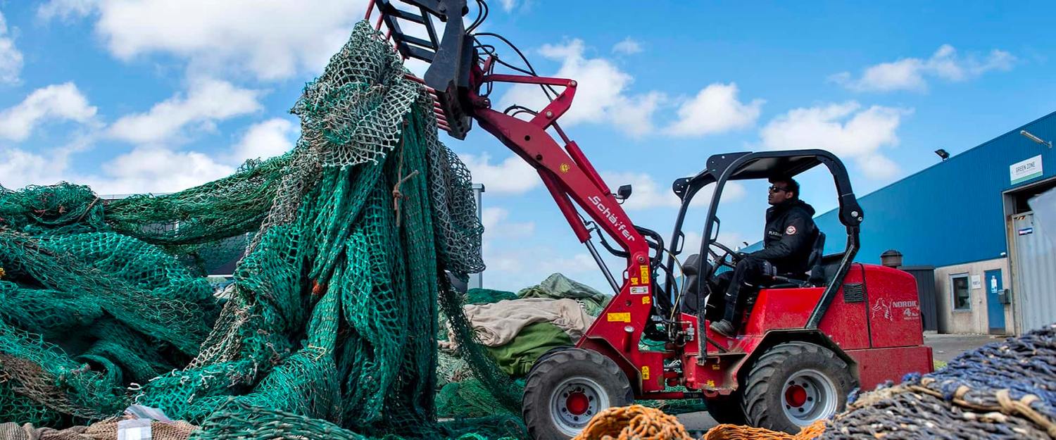 Photo of a JCB moving a large mound of discarded fishing nets