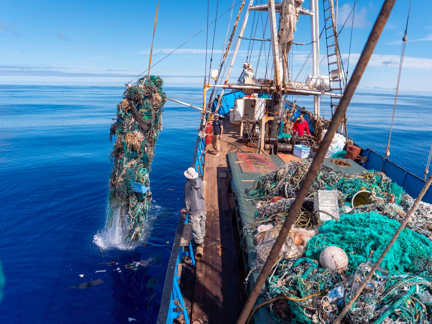 Boat hauling old fishing nets out of the ocean via a crane